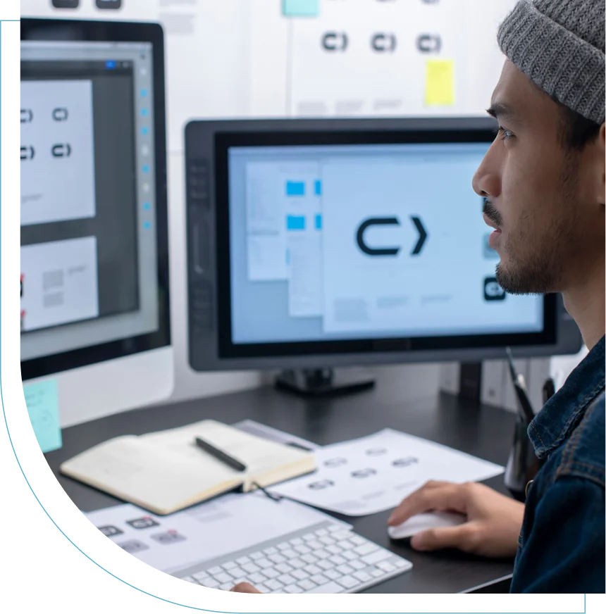 Designer working on logo creation using dual monitors and a graphics tablet.